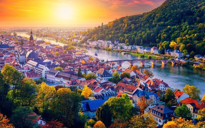 Heidelberg cityscape with Neckar River and Old Bridge during sunset, view from hillside.