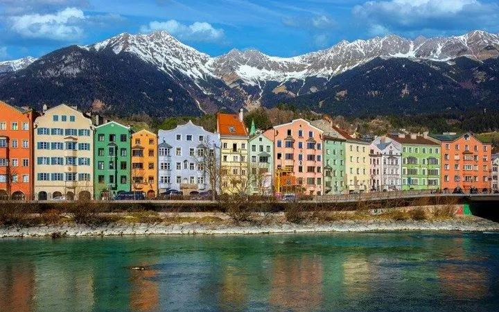 Colorful buildings along the Inn River with mountains in Innsbruck, Austria.