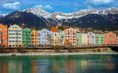 Colorful buildings along the Inn River with mountains in Innsbruck, Austria.