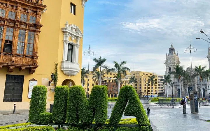 Lima cityscape with historic architecture and "LIMA" topiary in Plaza Mayor.