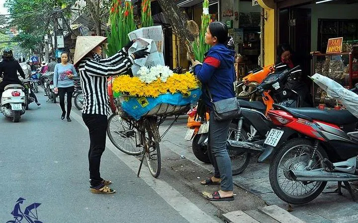 Hanoi street vendor selling flowers from a bicycle in the Old Quarter.