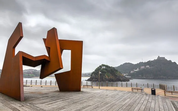 Sculpture on San Sebastian promenade with island view, part of self-guided walking tour.