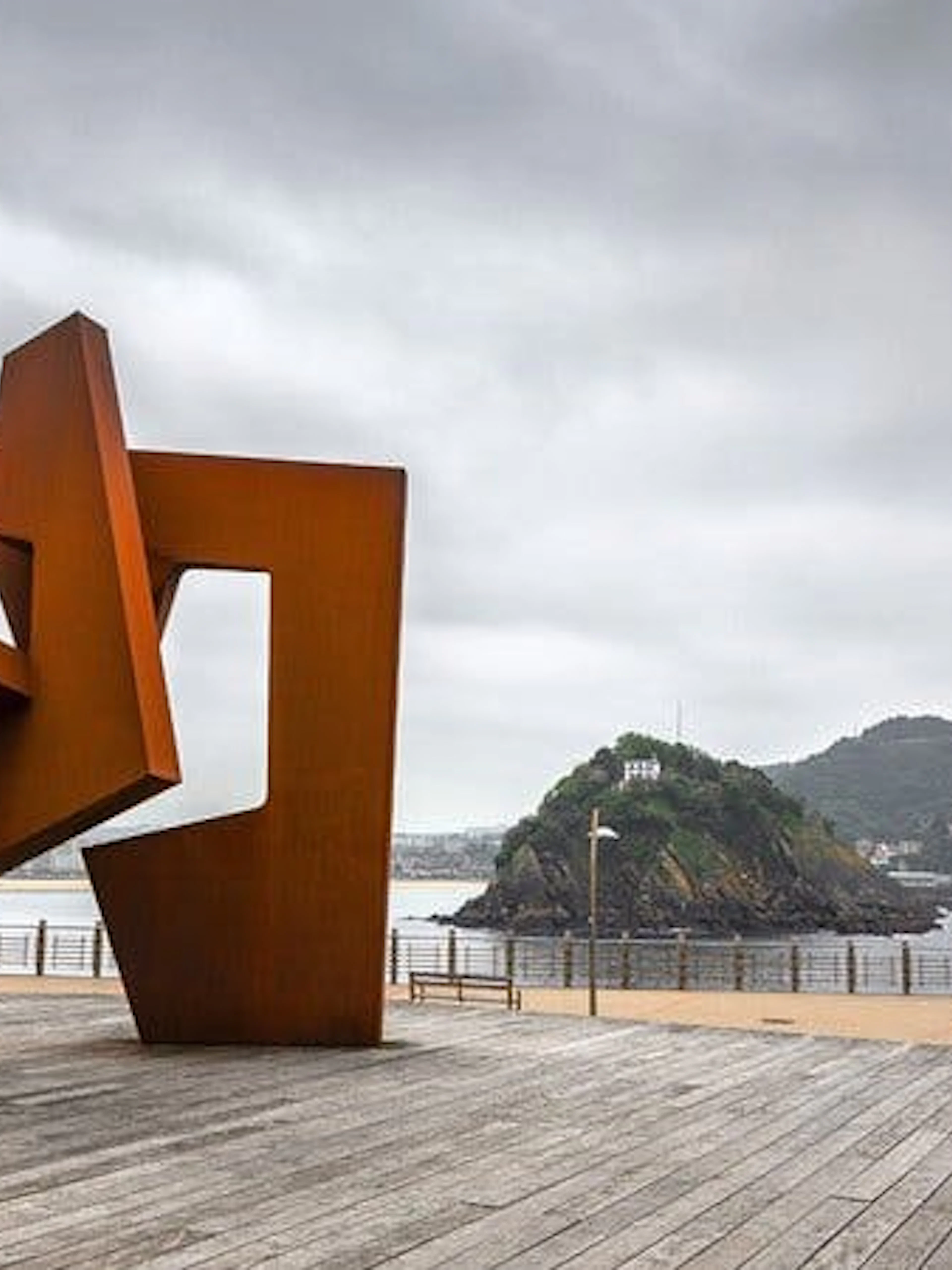 Sculpture on San Sebastian promenade with island view, part of self-guided walking tour.