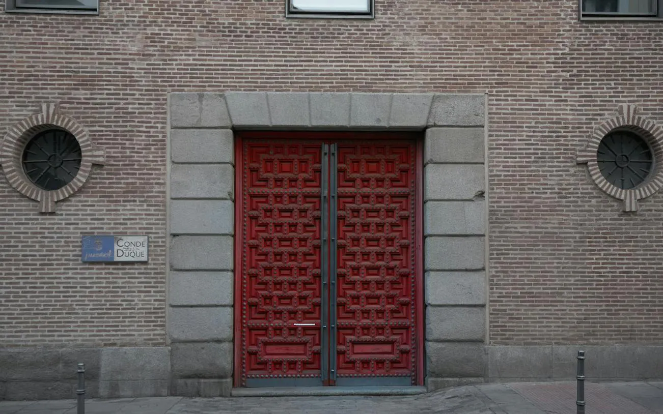 Conde Duque entrance with red ornate doors, Madrid Malasaña and Chueca audio walk.