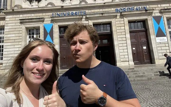 Visitors giving thumbs up outside Université de Bordeaux during self-guided city exploration game.