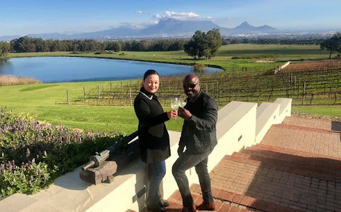 Couple enjoying wine with vineyard and mountain view in Durbanville Winelands.