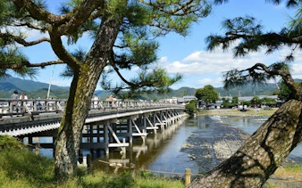 Togetsukyo Bridge over Katsura River in Arashiyama, Kyoto, surrounded by trees.