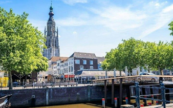 Breda cityscape with Grote Kerk tower and canal, featured in self-guided audio tour.