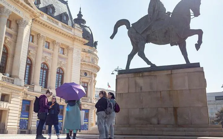 Group of tourists near equestrian statue in Bucharest Old Town during city highlights walking tour.