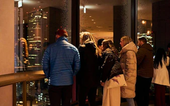 Group observing Tokyo skyline from Shinjuku skyscraper during night tour.