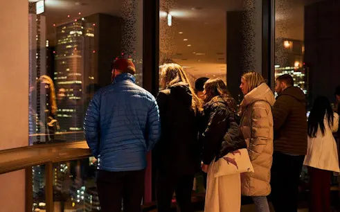 Group observing Tokyo skyline from Shinjuku skyscraper during night tour.