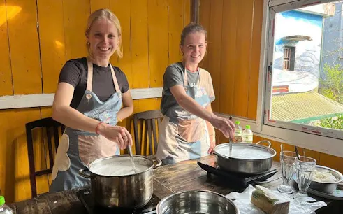 Tofu-making class in Sa Pa with participants stirring soy milk in pots.