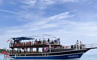 Boat with tourists on Antalya Lower Duden Waterfall tour, clear sky, Turkey.