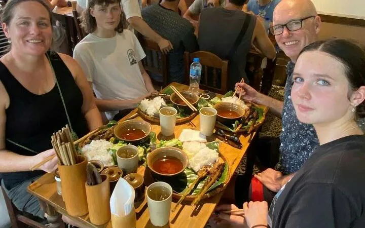 Group enjoying traditional Vietnamese street food in Hanoi during motorbike tour.