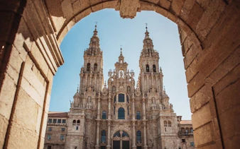 Santiago de Compostela Cathedral framed by stone archway on a sunny day.