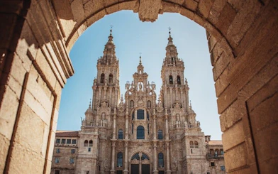 Santiago de Compostela Cathedral framed by stone archway on a sunny day.