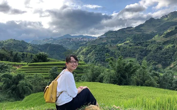 Person sitting on a hill overlooking terraced rice fields in Sapa, Vietnam.