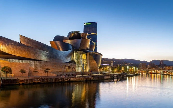 Guggenheim Museum Bilbao at dusk, reflecting on the Nervión River.