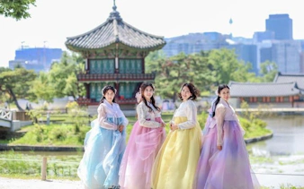 Women in colorful hanboks posing at a traditional pavilion in Seoul palace garden.
