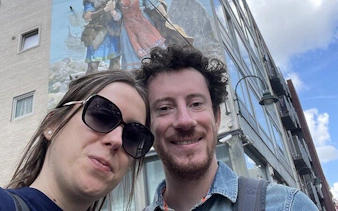 Couple in front of a comic mural in Brussels during a self-guided city exploration game.