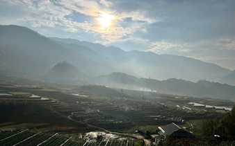 Terraced rice fields in Sapa with misty mountains and sunrise, Vietnam.
