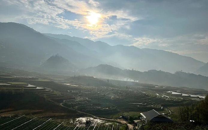 Terraced rice fields in Sapa with misty mountains and sunrise, Vietnam.
