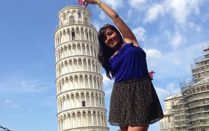 Leaning Tower of Pisa with a visitor posing in front, Italy.