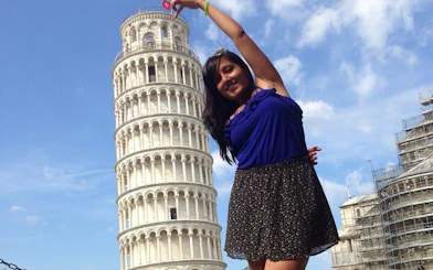 Leaning Tower of Pisa with a visitor posing in front, Italy.