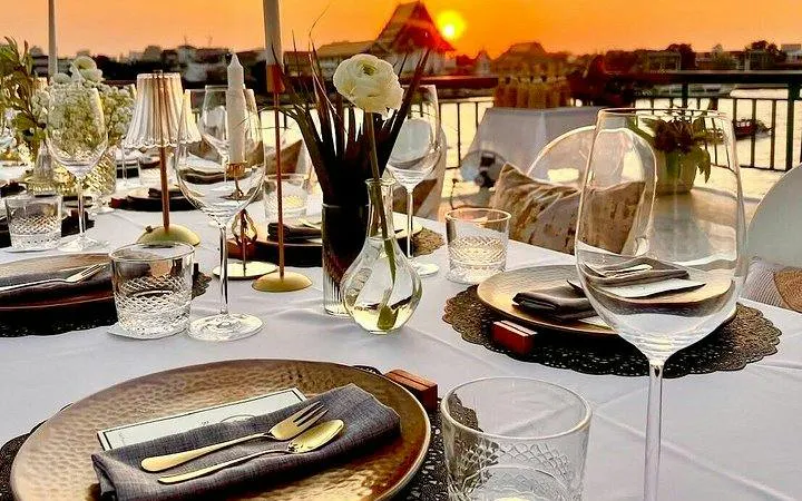 Fine dining setup by Chao Phraya River at sunset, Bangkok.