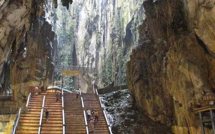 Staircase leading to Batu Caves entrance in Kuala Lumpur, surrounded by limestone formations.