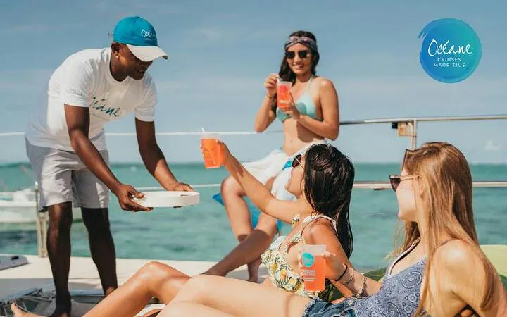 Catamaran cruise guests enjoying drinks on deck, Île aux Cerfs, Mauritius.