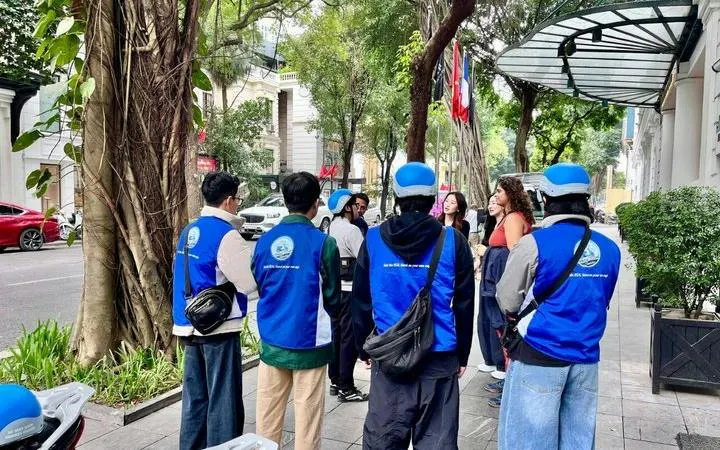 Group of tourists with guides in blue vests on Hanoi E-Scooter City Tour, Vietnam.