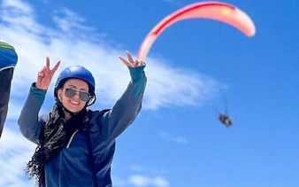 Paraglider in flight over Atlas Mountains with clear blue sky, Marrakesh.