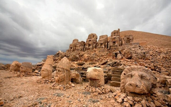 Ancient stone heads and statues at Mount Nemrut, Turkey, under a cloudy sky.