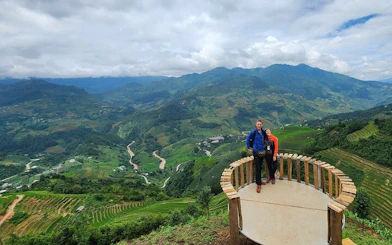 Trekking tourists on a viewpoint overlooking terraced rice fields in Mu Cang Chai, Vietnam.