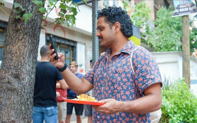 Man photographing tacos on a street in Mexico City.