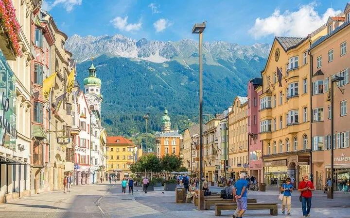 Street view of Innsbruck with colorful buildings and Alps in the background, part of the 10-day Alps tour.
