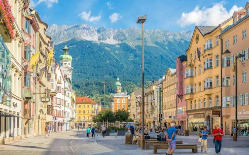 Street view of Innsbruck with colorful buildings and Alps in the background, part of the 10-day Alps tour.