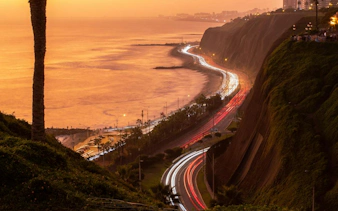 Coastal view of Lima's Barranco district at sunset with winding road and ocean.