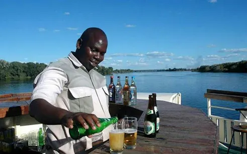 Bartender pouring drinks on Zambezi River cruise, Victoria Falls.