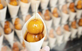 Dango skewers in a paper cone at a Kyoto street food stall during Arashiyama walking tour.