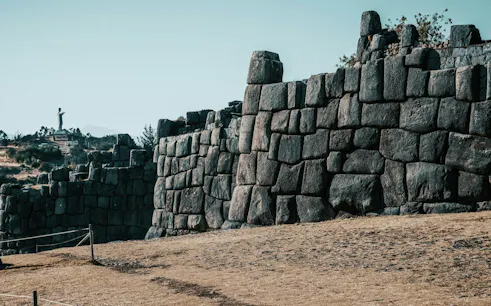 Sacsayhuamán stone walls with Cristo Blanco statue in the distance, Cusco.