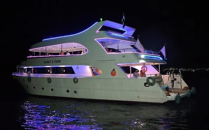 Sharm El Sheikh boat illuminated at night for seafood dinner cruise with entertainment.