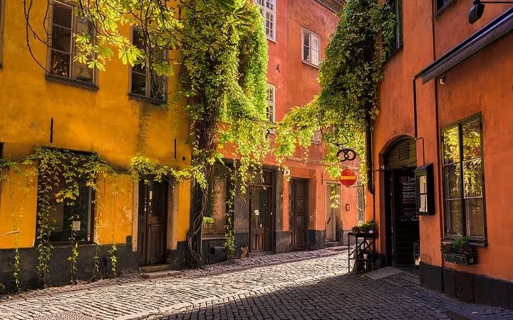 Cobblestone street in Stockholm's Gamla Stan with colorful historic buildings.