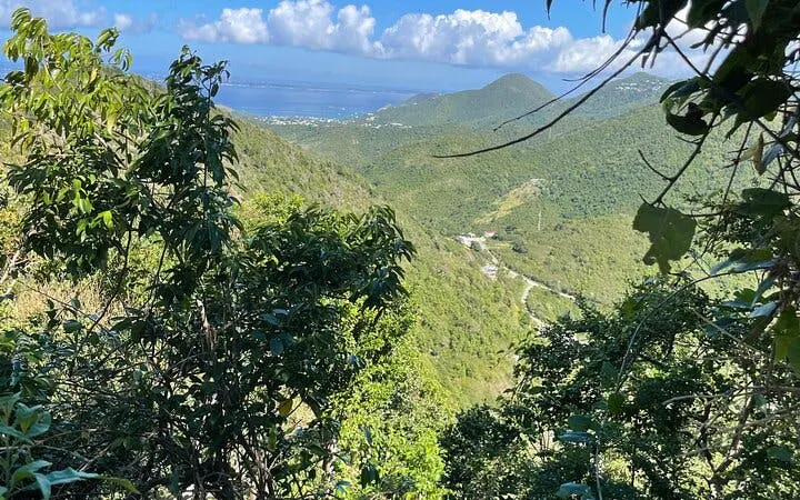 St. Maarten lush green hills with ocean view from highest point on guided hike.