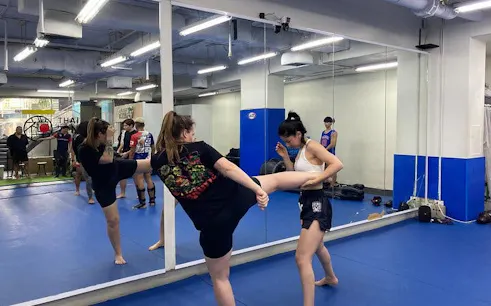 Muay Thai training session in Bangkok gym with participants practicing kicks.