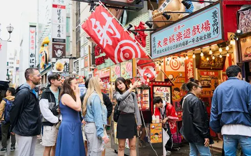 Tourists exploring vibrant Dotonbori street in Osaka during guided walking tour.