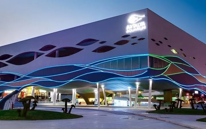 Antalya Aquarium exterior with colorful wave-like lights at dusk.