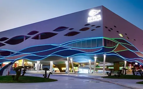Antalya Aquarium exterior with colorful wave-like lights at dusk.