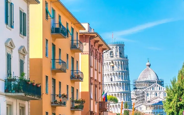 Leaning Tower of Pisa and Pisa Cathedral behind colorful buildings in Pisa, Italy.